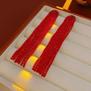 Close-up of red rhinestone fringe earrings in a cream-colored jewelry box gift display
