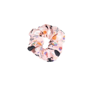 Pink fabric Halloween scrunchie with ghost, pumpkin, and bat patterns on white background