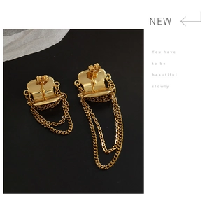 Detailed close-up of golden asymmetric tassel earrings with geometric brass plates