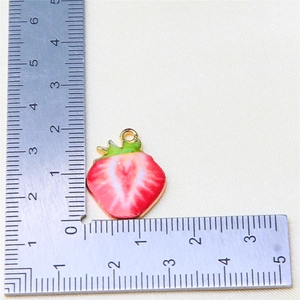 Detailed view of red strawberry fruit charm with gold trim and scale for size reference