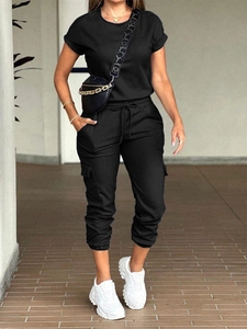 Outdoor full body shot of a woman wearing a black short sleeve cargo jumpsuit with pockets
