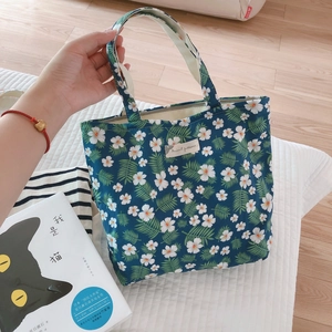 Detail of floral canvas tote bag featuring green daisy print and sturdy fabric handles