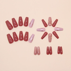 Detail of coffin-shaped press-on nails with rose red hearts, florals, and rhinestones