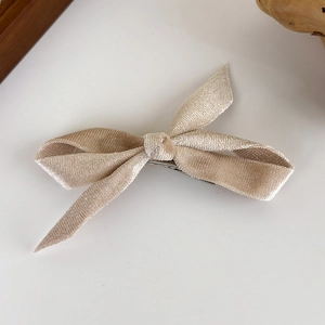 Detailed texture of champagne velvet bow hair clip with secure metal duckbill attachment