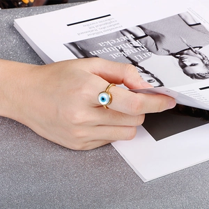 Close-up of 18K gold plated evil eye pearl ring worn by a model browsing a magazine