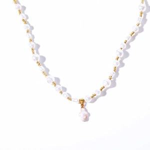 Collier en perles baroques avec perles dorées et un pendentif croix rose sur fond blanc