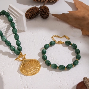 Vintage dark green beaded jewelry set with shell pendant on a natural background