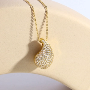 Water drop necklace plated in 18k gold with full pavé cubic zirconia on a minimalist stand