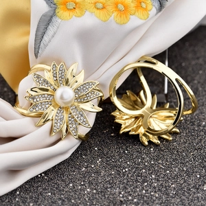 Macro detail of a golden sunflower scarf clip with rhinestones and central faux pearl