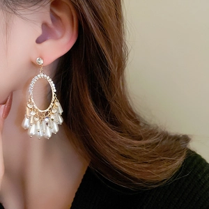 Gros plan sur des boucles d'oreilles vintage en or avec strass et glands de perles