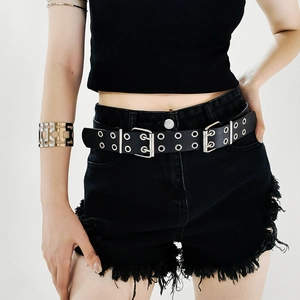 Detail of black double-prong buckle belt with metal eyelets and golden geometric bracelet