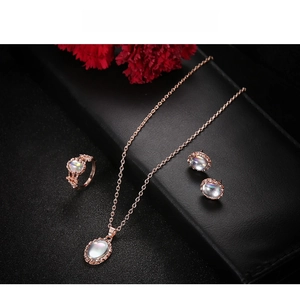 Detailed set of rose gold necklace, ring and earrings with opal-like stones on black display