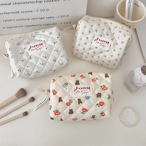 Détail de trousses à maquillage matelassées aux motifs cerise, fleurs et ours avec fermetures