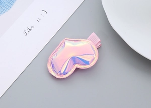 Detail of pink holographic heart-shaped hair clip with smooth finish on fabric base