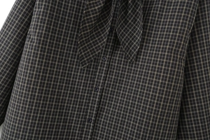Detail of plaid shirt with front buttons and stylish bow tie neckline design