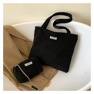Detail of black corduroy tote bag and mini crossbody pouch with golden chain link strap
