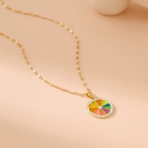 Golden stainless steel necklace featuring a colorful rainbow fruit slice pendant on beige background