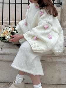 Elegant white knit cardigan with pink rose accents and matching plush skirt for autumn style