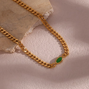 Detailed macro of 18K gold plated Cuban link chain with a green oval pendant stone