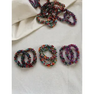 Colorful faceted crystal elastic hair rings set with multi-color beads on linen background