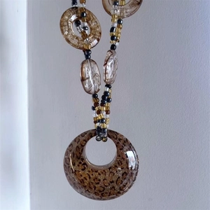 Detailed shot of resin leopard print round pendant necklace with bronze feather charms