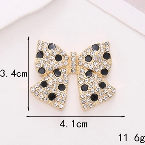 Detail of gold bow charm with white rhinestones and black dots, 4.1cm width size display