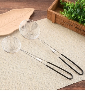 Close-up of stainless steel skimmer spoons with black handles on a beige woven mat