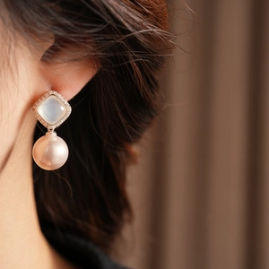 Detail view of pearl earrings with square stones and champagne pearls on model