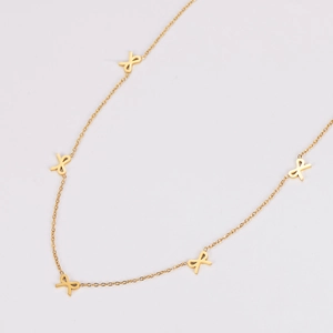 Macro detail of gold-plated necklace featuring five elegant butterfly bow charms on a chain