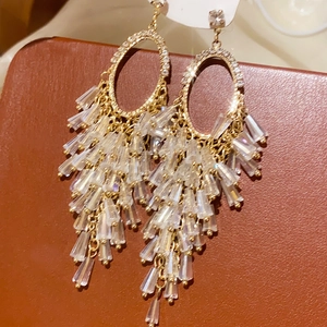 Detail of vintage gold bow earrings with crystal tassels on brown leather background