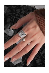 Macro detail of silver S925 ring with irregular liquid metal texture on charcoal background