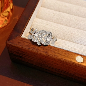 Détail d'une bague plume en argent sertie de zircones sur un coffret à bijoux en bois foncé