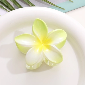 Detail of yellow and white gradient plumeria hair claw clip on a white decorative plate