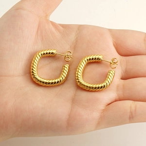 Macro shot of gold-plated twisted rope earrings held in hand to show size and texture