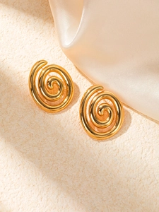 Gros plan de boucles d'oreilles spirales plaquées or en acier titane sur fond de soie douce