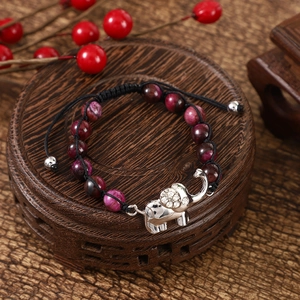 Detail of 8mm tiger eye beads and silver elephant charm with rhinestones on a wooden stand