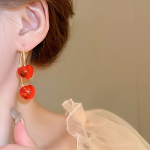Close-up of a model wearing sweet cherry earrings with red beads and gold metal pins
