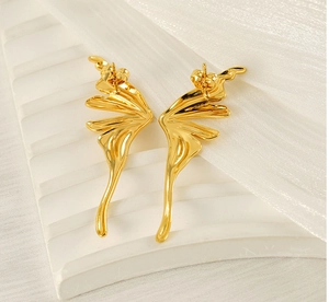 Detailed view of gold butterfly wing earrings on a textured display with soft lighting