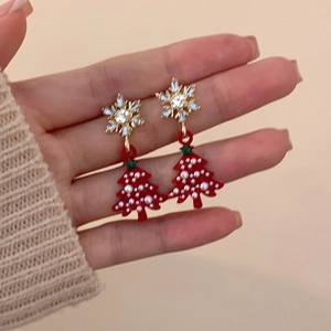 Snowflake and red Christmas tree pearl earrings with rhinestone accents in hand