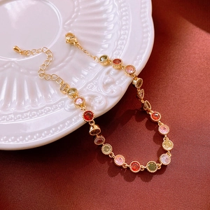 Détail d'un bracelet doré avec des zircons multicolores et un pendentif goutte ajustable