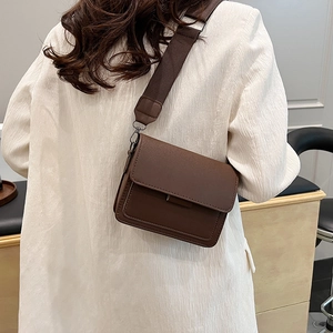 Classic brown crossbody square bag with wide shoulder strap shown on a white outfit