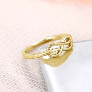 Detailopname van gouden ring met oneindigheidssymbool op een witte marmeren sokkel