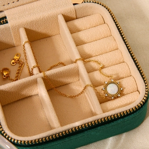Detail of 18K gold-plated sun pendant with opal stone in a green jewelry box
