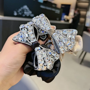 Detailed macro view of satin scrunchies with crystal bow accents in black and champagne gold