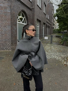 Détail d'un manteau cape en laine gris foncé avec col montant et ceinture nouée
