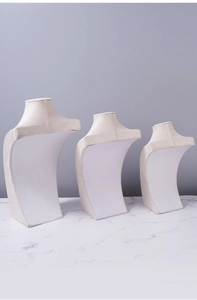 Three-tier beige velvet mannequin necklace display stands on marble surface