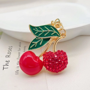 Creative red crystal cherry keychain with green leaves and gold alloy accents on white plate