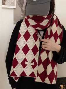 Détail de l'écharpe en tricot à losanges rouge et crème avec étiquette logo de qualité
