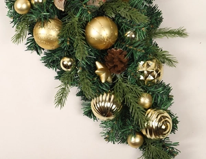 Detail von goldenen Weihnachtskugeln, Zapfen und grünen Tannennadeln an einem Festgehänge
