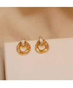 Detailed macro view of triple interlocking gold circles earrings with crystal pavé on satin